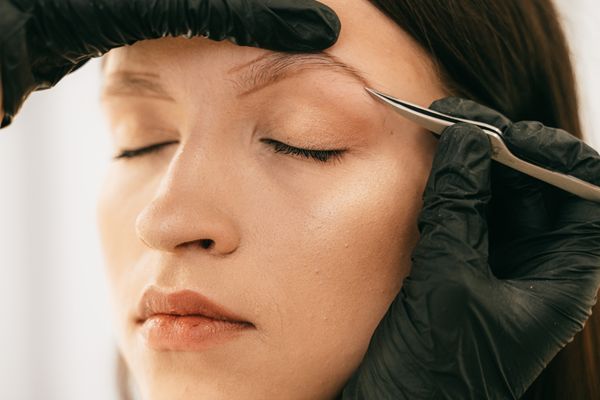 A client receiving precise eyebrow shaping in a beauty studio