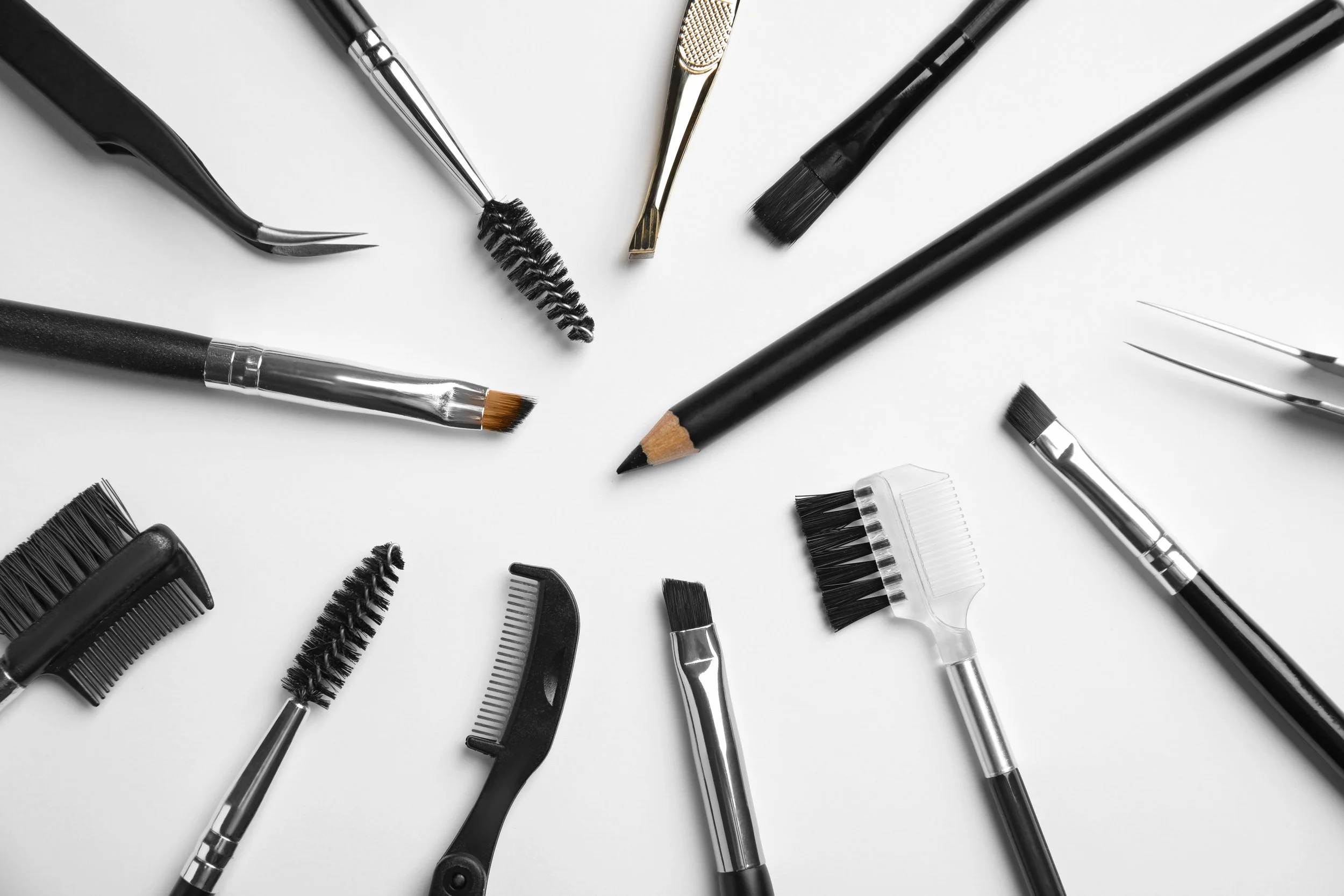 Professional eyebrow brushes and shaping tools arranged on a clean surface